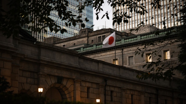A Japanese national flag flies outside the Bank of Japan (BOJ) headquarters in Tokyo, Japan, on Wednesday, Oct. 26, 2022. Bank of Japan Governor Haruhiko Kuroda appears as determined as ever to see out his inflation mission without buckling to market or political pressure. Photographer: Noriko Hayashi/Bloomberg