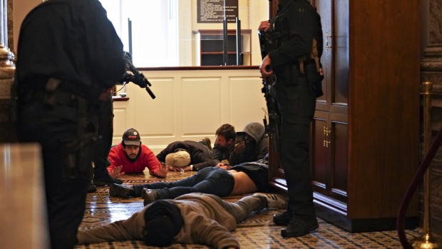 U.S. Capitol police officers detain demonstrators outside the House Chamber during a joint session of Congress to count the votes of the 2020 presidential election in Washington, D.C., U.S., on Wednesday, Jan. 6, 2021. The U.S. Capitol was placed under lockdown and Vice President Mike Pence left the floor of Congress as hundreds of protesters swarmed past barricades surrounding the building where lawmakers were debating Joe Biden's victory in the Electoral College. Photographer: Stefani Reynolds/Bloomberg
