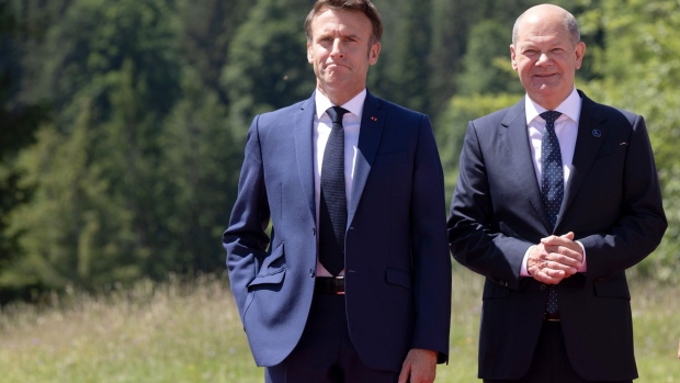 Emmanuel Macron, France's president, left, welcomed by Olaf Scholz, Germany's chancellor, on the opening day of the Group of Seven (G-7) leaders summit at the Schloss Elmau luxury hotel in Elmau, Germany, on Sunday, June 26, 2022. Issues on Sunday's formal agenda include the global economy, infrastructure and investment and foreign and security policy, while a number of bilateral meetings are also planned. Photographer: Liesa Johannssen-Koppitz/Bloomberg