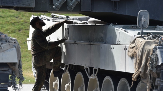 A soldier climbs on to a Leopard battle tank during military exercises in Germany. Photographer: Christof Stache/AFP/Getty Images