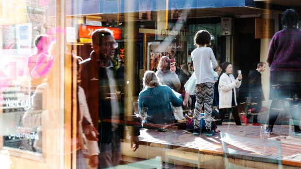 Pedestrians are reflected in a store window in Wellington, New Zealand, on Saturday, June 22, 2019. The out-of-favor kiwi dollar has tumbled about 3% this quarter as the Reserve Bank of New Zealand turned dovish and cut interest rates, the first central bank in the developed world to do so. Economic growth held at a five-year low in the three-months through March, leaving the door open for further easing.