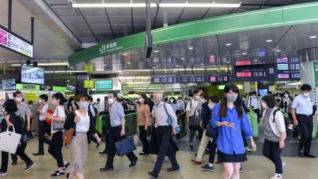 Morning commuters wearing protective face masks walk at the entrance of Shinjuku station in Tokyo, Japan in Tokyo, Japan, on Thursday, July 2, 2021. While the number of infections directly connected with the Olympics has so far been relatively low, Tokyo and its surrounding areas are experiencing their worst-yet virus wave. Photographer: Noriko Hayashi/Bloomberg