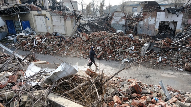 A woman walks by destroyed buildings 20 miles west from the front lines of fighting on January 20, 2023 in the Donetsk Region, Ukraine.