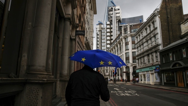 A pedestrian holds an umbrella, featuring the design of the European Union (EU) flag, in London. Photographer: Hollie Adams/Bloomberg