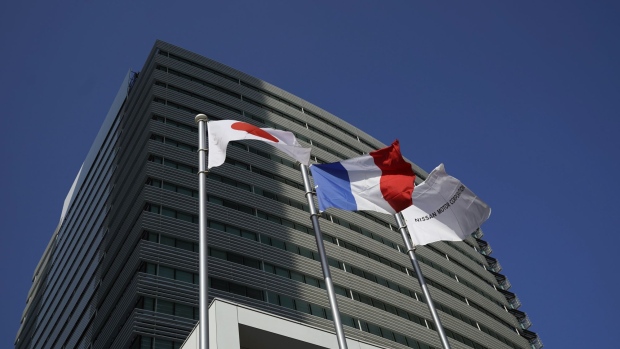 A corporate flag of Nissan Motor Co., right, flies alongside the flags of Japan, left, and France outside the automaker's headquarters in Yokohama. Photographer: Toru Hanai/Bloomberg