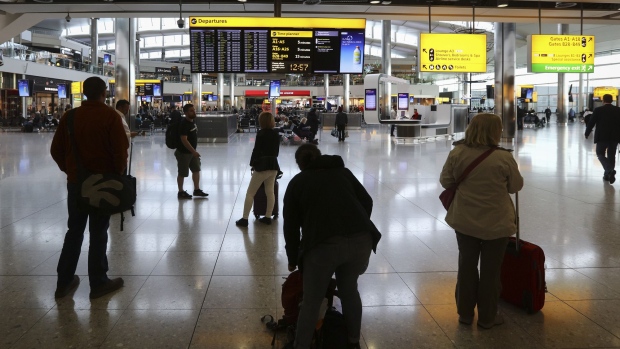 Passengers look at a departure information board inside London Heathrow airport's Terminal 2, in London, U.K., on Friday, Oct. 7, 2016. Europe's busiest hub is stepping up its pitch for a new runway with a much-delayed U.K. government decision on where to locate additional flight capacity for southern England likely to announced in the coming weeks. Photographer: Simon Dawson/Bloomberg