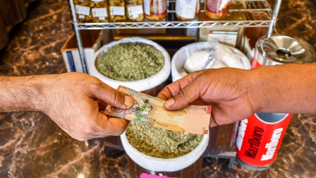 A customer pays for a purchase with a ten Kuwaiti dinar banknote in a grocery store in Kuwait City, Kuwait, on Wednesday, July 13, 2022. Global warming is smashing temperature records all over the world, but Kuwait — one of the hottest countries on the planet — is fast becoming unlivable.