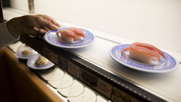 An employee selects a plate of tuna sushi from a conveyor belt at a Kura Corp. sushi restaurant in Kaizuka, Osaka prefecture, Japan, on Thursday, Aug. 17, 2017. Kura operates a revolving sushi restaurant chain based in Osaka.