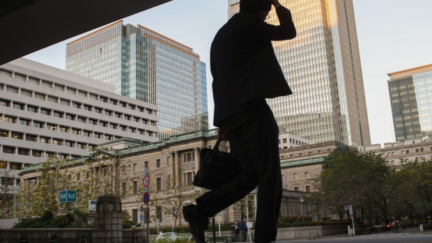 A pedestrian in front of the Bank of Japan (BOJ) headquarters at dusk in Tokyo, Japan, on Wednesday, Oct. 26, 2022. Bank of Japan Governor Haruhiko Kuroda appears as determined as ever to see out his inflation mission without buckling to market or political pressure. Photographer: Noriko Hayashi/Bloomberg