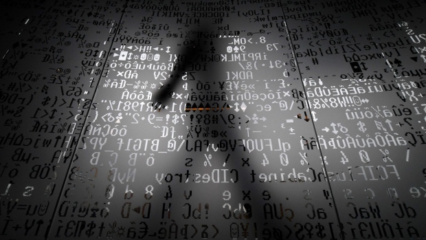 A person walks behind a wall with machine coding symbols. Photographer: Kirill Kudryavtsev/AFP/Getty Images