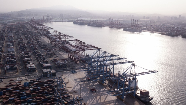 Cargo ships are moored under cranes as shipping containers stand at the Qingdao Qianwan Container Terminal in this aerial photograph taken in Qingdao, China, on Monday, May 7, 2018. China's overseas shipments exceeded estimates while imports surged, as the global economy continued to support demand.