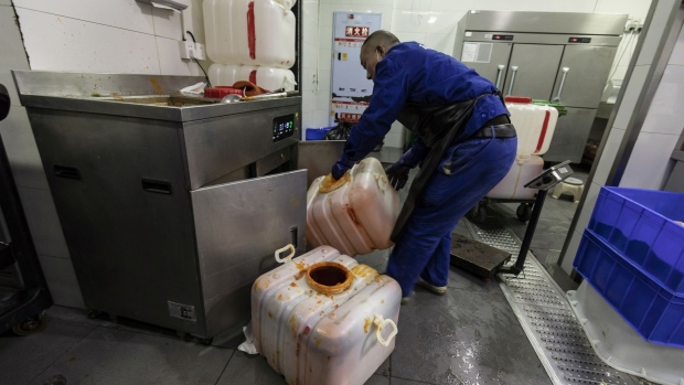 A worker collects vats of hot pot waste oil at a restaurant in Chengdu. Photographer: Qilai Shen/Bloomberg