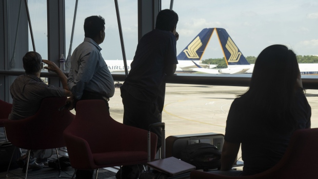 Travelers in a waiting area near Singapore Airlines Ltd. aircraft at Changi Airport. Photographer: Ore Huiying/Bloomberg