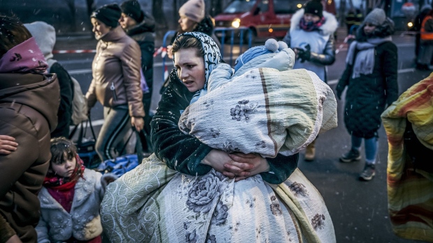 March 2, 2022. A Ukrainian woman carries a child in a blanket after crossing the border in Siret, Romania. Photographer: Andrei Pungovsch/Bloomberg