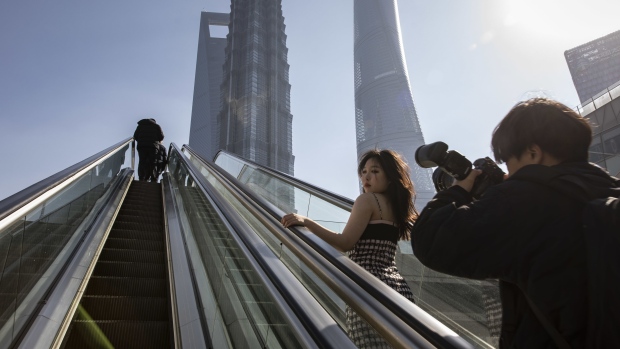 A woman poses for photos in Pudong's Lujiazui Financial District in Shanghai, China, on Monday, Jan. 30, 2023. China's stocks pulled back from the verge of a bull market, with the muted reopening from a week-long Lunar New Year break indicating that traders are waiting on new catalysts. Photographer: Qilai Shen/Bloomberg
