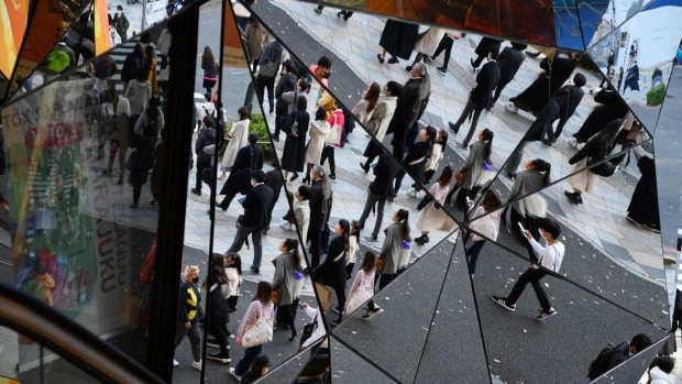 Pedestrians are reflected in mirrors at the entrance to the Tokyu Plaza Omotesando Harajuku shopping complex in Tokyo, Japan, on Friday, Dec. 9, 2022. Economists forecast that Japan’s economy will return to growth again this quarter, pushed up by private sector investment and consumption. Photographer: Akio Kon/Bloomberg 
