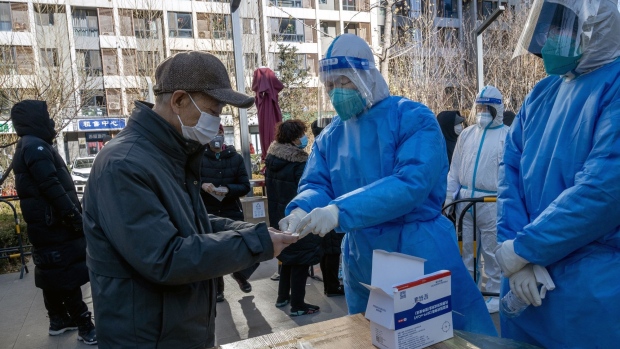 A worker in protective gear hands out a Covid rapid antigen test kit to a resident at a testing station in Beijing in 2022. Education authorities are being cautious about illness, even after Covid Zero. Source: Bloomberg