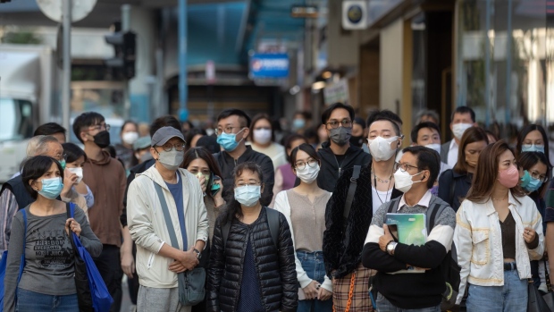 Pedestrians wearing protective face masks in Hong Kong, China, on Thursday, Dec. 8, 2022. Hong Kong — which reported the most Covid infections since March — has been slowly rolling back the Covid rules that have kept it isolated from the world throughout the pandemic, battered its standing as a global financial hub and hurt economic growth. Photographer: Paul Yeung/Bloomberg