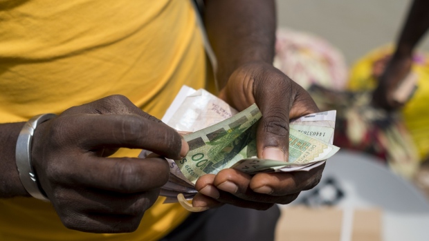 A man counts out West African CFA franc currency banknotes by the fishing harbour in the port area of Bissau, Guinea-Bissau, on Saturday, Feb. 10, 2018. The International Monetary Fund (IMF) said an increase in public and private investment would provide new growth impetus for the West African nation. Photographer: Xaume Olleros/Bloomberg