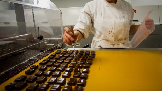 Chocolates come out of a machine after receiving a coating at a factory in Brooklyn, New York. Photographer: Ron Antonelli/Bloomberg