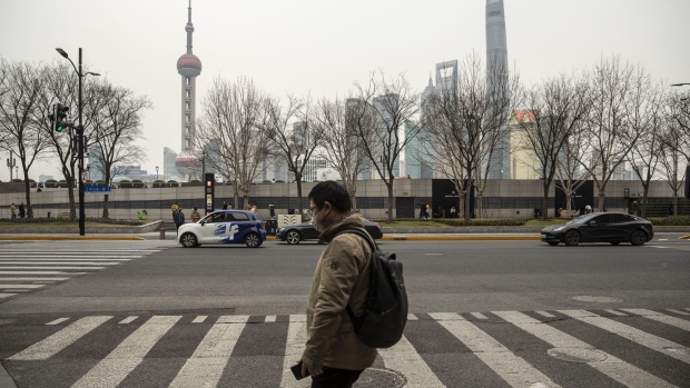 A pedestrian crosses a street near the Bund across from buildings in Pudong's Lujiazui financial district in Shanghai, China, on Tuesday, Feb. 28, 2023. After three years of turbulence under the Covid pandemic, China's leaders are expected to lay out economic goals to get growth back on track, restore confidence and avoid a build-up of financial risks. Photographer: Qilai Shen/Bloomberg