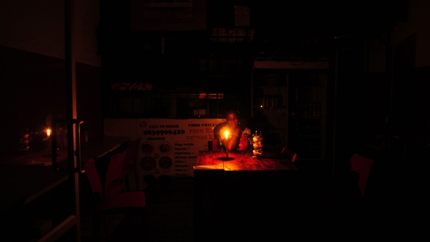 A customer waits for food by candlelight in a restaurant during a loadshedding power outage period, in Johannesburg, South Africa, on Monday, Feb. 13, 2023. Eskom Holdings SOC Ltd., which supplies most of South Africa’s power from coal-fired plants, has been implementing rolling blackouts since 2008 because it can’t meet demand.
