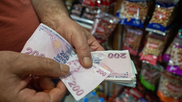 A customer counts out 200 Turkish lira banknotes for a purchase in Istanbul, Turkey, on Friday, June 24, 2022. Tourism arrivals in May surged 308% year-on-year, boosting hopes that a rebound in the sector can support the weakening Lira.