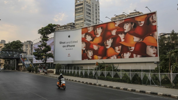 A motorcyclist rides past a billboard for the Apple Inc. iPhone in Mumbai. Photographer: Dhiraj Singh/Bloomberg