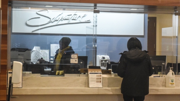 A worker assists a customer at a Signature Bank branch in New York, US, on Monday, March 13, 2023. The sudden closure of New York's Signature Bank by state regulators Sunday underscored the urgency of extraordinary US efforts to backstop the nations banking system and quell mounting concerns among customers about the safety of their deposits.