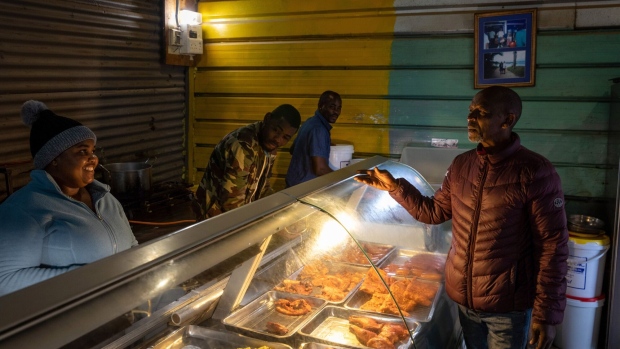 A light illuminates a food store in the Imizamo Yethu informal settlement in the Hout Bay district of Cape Town, South Africa, on Wednesday, Aug. 3, 2022. South Africa's state-owned power utility Eskom Holdings SOC Ltd. warned it may have to implement rolling blackouts for the first time in more than a week due to a shortage of generation capacity.
