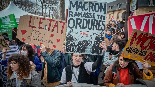 Protestors hold placards that read "Macron pick up your trash" and "The State is trash." They chanted as they demonstrated through the streets of Paris against the French Government's plans to increase the retirement age in France from 62 to 64 on March 15. Photographer: Kiran Ridley/Getty Images Europe