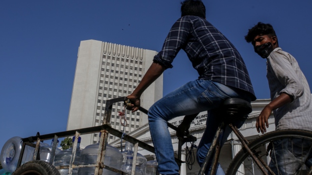 A cyclist transports empty water bottles near the Reserve Bank of India (RBI) headquarters, left, in Mumbai, India, on Saturday, Feb. 5, 2022. The RBI is set to outline its policy on Feb. 9 and is expected to take further steps like raising the reverse repo rate to further pull back on pandemic-era steps. Photographer: Dhiraj Singh/Bloomberg