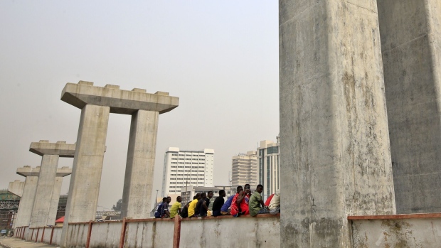 People sit on a ledge between mono rail line pillars under construction in Lagos, Nigeria, on Saturday, Feb. 16, 2019. A last-minute delay of Nigeria’s general elections by a week has thrown Africa’s biggest democracy into disarray and carries dangers for both President Muhammadu Buhari and his main opponent, Atiku Abubakar. Photographer: George Osodi/Bloomberg