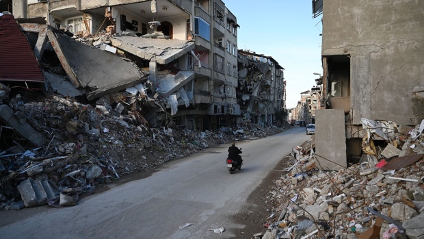 A man rides his motorcycle in a destroyed neighborhood among the rubble of collapsed buildings in Hatay, on March 7, 2023, one month after a massive earthquake struck southeastern Turkey. Photographer: Ozan Kose/AFP/Getty Images