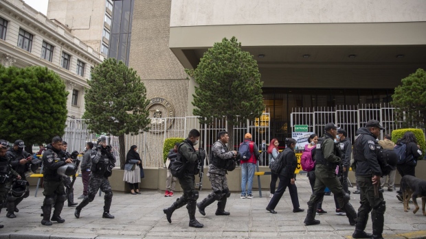 Police officers stand guard as residents wait in line outside of the Bolivian Central Bank in La Paz, Bolivia, on Wednesday, March 8, 2023. Bolivians formed a line three blocks long outside the central banks headquarters in La Paz on Wednesday as locals rush to convert their savings into dollars amid a growing sense of unease in the Andean nation.