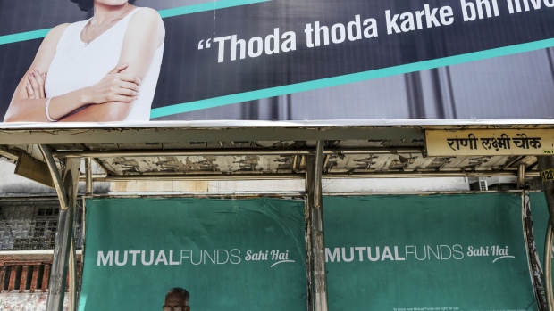 A passenger sits below an advertisement for the Mutual Funds Sahi Hai campaign by the Association of Mutual Funds in India (AMFI) at a bus stop in Mumbai, Maharashtra, India, on Thursday, May 18, 2017. Flows into mutual funds from towns outside India's 15 biggest cities surged 41 percent to a record 3.1 trillion rupees ($48 billion) at the end of March, according to the latest data from the AMFI.