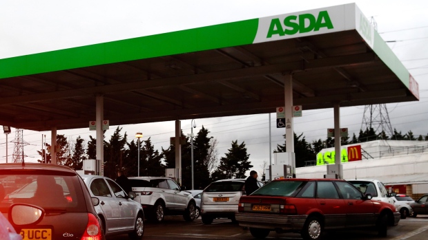 Cars wait in line to re-fuel at an ASDA Group Ltd. supermarket gas station in Croydon, UK.  Photographer: Luke MacGregor/Bloomberg