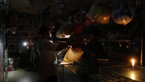 A worker uses a candle to continue business during the power outage in Dhaka in Oct. 2022.
