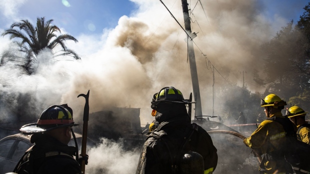 Firefighters work to extinguish a structure fire in the Montclair Hills neighborhood of Oakland, California, U.S., on Tuesday, Oct. 27, 2020. The preliminary cause of the fire was an overloaded generator, according to the Oakland Fire Department. PG&E Corp. cut power in the area to prevent live wires from falling into dry brush during the wind storms that have parts of the East Bay under a Red Flag Warning.