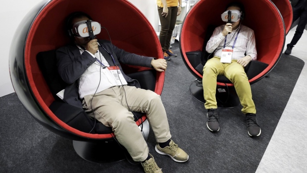 Attendees wear virtual reality (VR) headsets while experiencing the 5G network technology at the KDDI Corp. booth at the Combined Exhibition of Advanced Technologies (CEATEC) in Chiba, Japan, on Wednesday, Oct. 16, 2019. CEATEC, the annual information technology and electronics trade show, will run until Oct. 18. Photographer: Kiyoshi Ota/Bloomberg