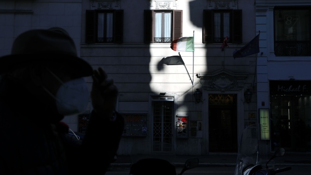 The Italian national flag flies outside a shop in Rome, Italy, on Tuesday, Jan. 26, 2021. Italian Prime Minister Giuseppe Conte will resign on Tuesday morning to avoid a damaging defeat in the Senate and maneuver for a return at the head of a new government. Photographer: Alessia Pierdomenico/Bloomberg