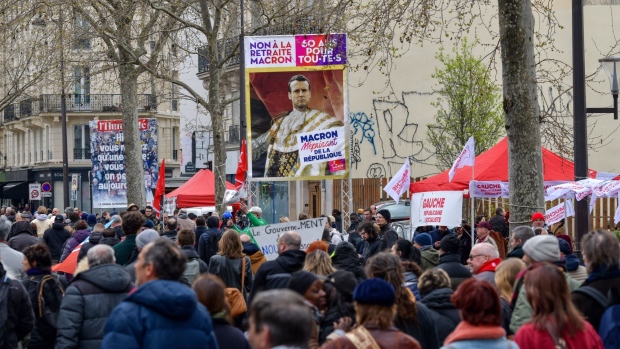 Demonstrators march past a billboard of Emmanuel Macron in Paris, on March 28. Photographer: Nathan Laine/Bloomberg