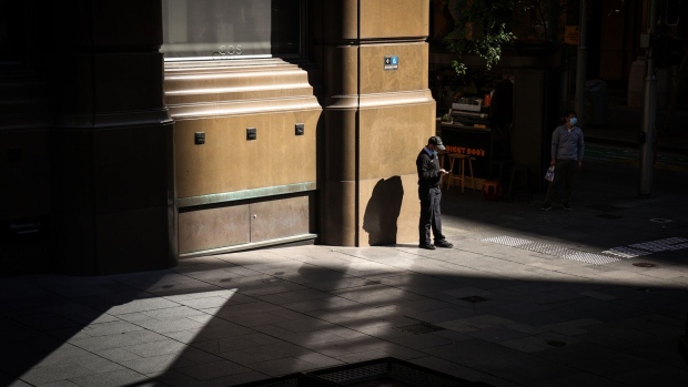 A security guard uses his phone at Martin Place near the Reserve Bank of Australia (RBA) building in Sydney, Australia, on Monday, Sept. 6, 2021. Australia's central bankers are set to revisit the question of whether to delay a planned taper of bond purchases as a worsening outbreak of the delta variant dims prospects of a rapid economic rebound. Photographer: David Gray/Bloomberg