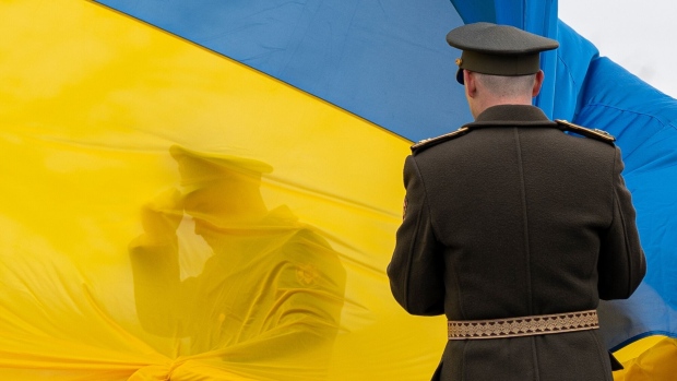 Ukrainian military personnel hold a Ukrainian national flag during an event to mark the anniversary of the city’s de-occupation in Bucha.