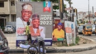 A worker arranges bags of water onto a cart in front of election posters for the All Progressive Congress (APC) presidential candidate Bola Tinubu and his running mate Kashim Shettima in the Yaba district of Lagos, Nigeria, on Monday, Feb. 6, 2023. Nigerians are gearing up to choose a successor to President Muhammadu Buhari, whose eight years in power have been blighted by economic decay, soaring unemployment, heightened insecurity and an exodus of the educated elite. Photographer: Benson Ibeabuchi/Bloomberg