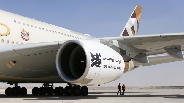 Attendees walk passed an Airbus SE A380 passenger aircraft, operated by Etihad Airways PJSC, as it stands on the tarmac during the 15th Dubai Air Show at Dubai World Central (DWC) in Dubai, United Arab Emirates, on Monday, Nov. 13, 2017. The biennial Dubai expo is an important venue for manufacturers to secure deals for their biggest and most expensive jetliners. Photographer: Natalie Naccache/Bloomberg