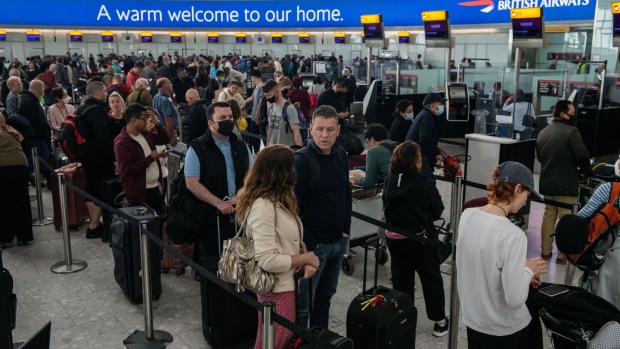 Passengers queue to check in at British Airways desks inside the departures hall of Terminal 5 at London Heathrow Airport in London, U.K., on Wednesday, April 13, 2022. Travel disruption continued to hit U.K. holidaymakers as officials warned of expected queues at airports later in the week and motorists faced fuel shortages. Photographer: Chris J. Ratcliffe/Bloomberg