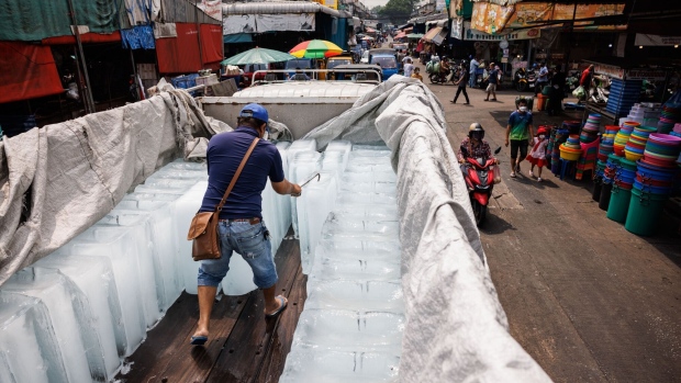 A worker handles a block of ice at a wet market during a heat wave in Bangkok on April 27. Photographer: Andre Malerba/Bloomberg