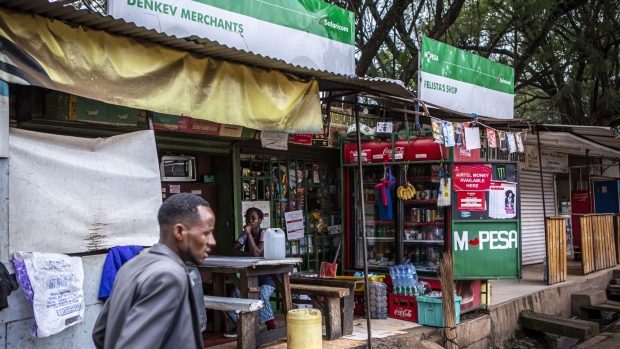 A pedestrian passes retail kiosks offering Safaricom Plc mobile money services in Nairobi, Kenya, on Tuesday, May 11, 2021. Revenue from M-Pesa, Safaricom's mobile-money service, is expected to grow after more customers have adopted cashless transactions during the coronavirus pandemic.