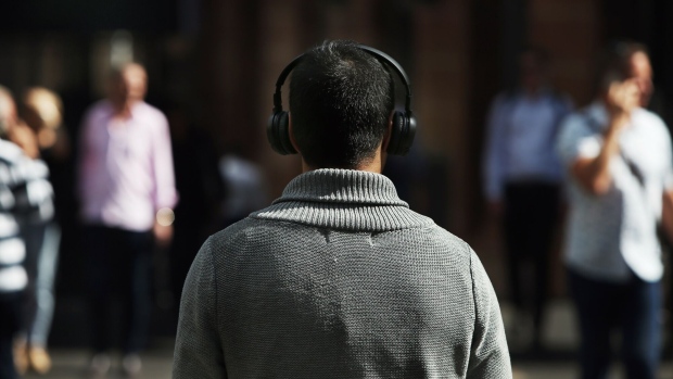 A pedestrian uses a headphone in the central business district in Sydney, Australia, on Friday, April 30, 2021. The government has tamed the virus by shuttering the international border and through rigorous testing and contact tracing, giving Australians an enviable level of freedom. But after winning the containment battle, the country now risks losing the vaccination war as supply shortages and a slow rollout jeopardise the economic recovery. Photographer: Lisa Maree Williams/Bloomberg